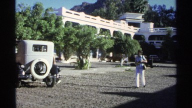 1975: Cars Parked and Two People Walking and Observing Something in Another Car