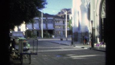 1975: a fairly empty street with a few people outside of a church. GUAYMAS