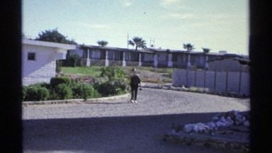 1975: a person walks away from one story buildings in a sunny day. GUAYMAS