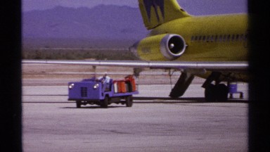 1974: a man is transporting several pieces of luggage around an airliner and