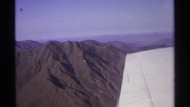 1974: barren brown mountains are seen from outside the window of a plane as it