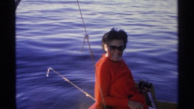 1975: a smiling lady in an orange sweater sit on a boat. GUAYMAS MEXICO