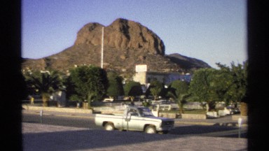 1975: a long road with water at a place and car or transports are moving fast at