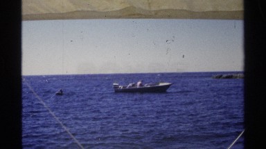 1975: a boat travel on the water and a man driving at high speed at morning