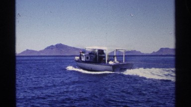 1975: a boat streaming on the water some people are at the boat to enjoying the