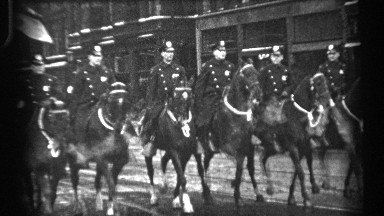 1937: A parade being led by police officers on horseback with Scottish musicians in kilts