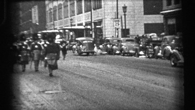 1937: people with long cap and uniform dress wearing and walking at the road and