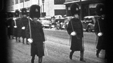1937: people are walking at the morning at the road and cars are parking at the