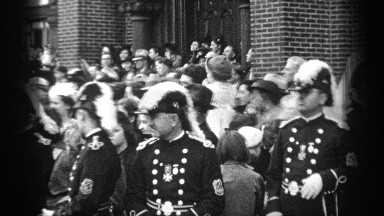 1937: civilians and soldiers standing in front of a brick building. CLEVELAND