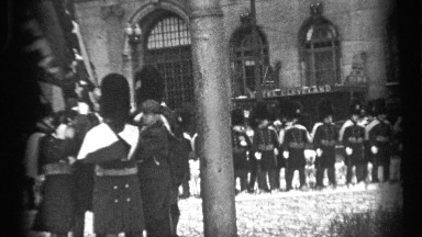 1937: officers standing outside a building on guard and handling a flag.
