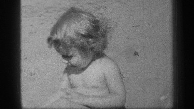 1938: a happy baby plays in the sand on the beach while dressed in a diaper