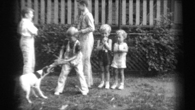 1938: two boys play catch while another boy plays tug with a dog and two younger