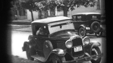 1938: a vehicle is passing beside a road in a residential area with a women,