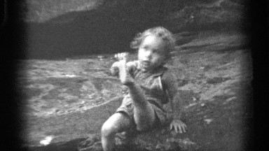 1938: little girl sitting on beach playing with her toes. CLEVELAND OHIO
