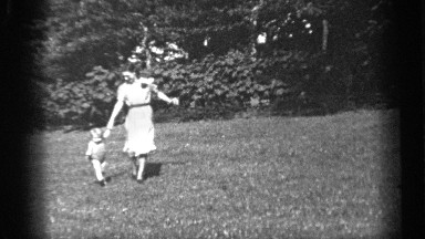 1938: woman gives young girl an apple after they run on grass holding hands