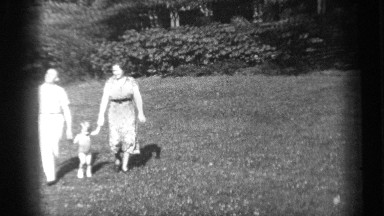 1938: small family: man woman and child walking across lawn holding hands