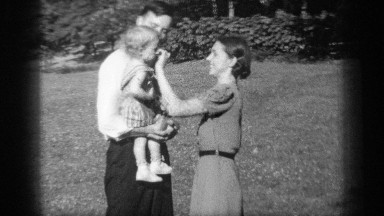 1938: a mother puts sunglasses on a female toddler held in her father's arms
