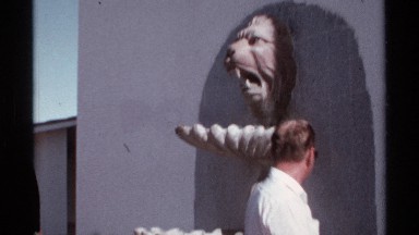 1974: a gentleman is walking past a unique sculpture mounted on tile of an