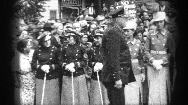 1937: persons dressed in uniforms and holding swords stand in line while an