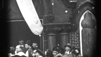 1937: A Crowd of People Stand Outside Smiling and Talking