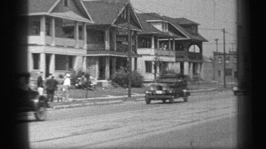1937: historic cars driving down the street in a fashion of parade down the city