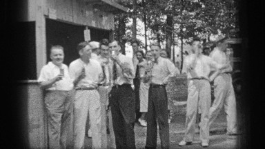 1937: group of mostly men hold small beverage containers by outdoor booth