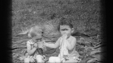 1937: two adorable little babies share one cup of liquid as the one on the left