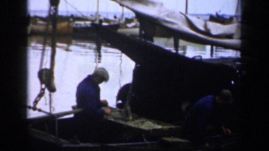 1957: Two Men in Blue Working Hard on a Docked Boat in the Netherlands