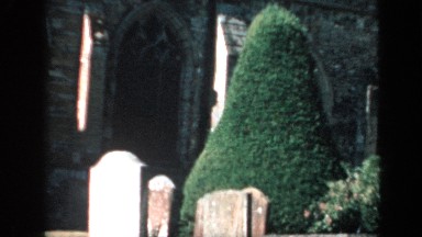 1957: view panning across a graveyard with a boy in the background ENGLAND