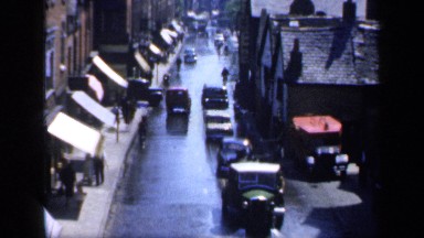 1957: automobiles and bicycles sharing a narrow, wet and busy street ENGLAND