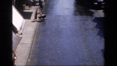 1957: woman pushing a baby carriage while crossing a street ENGLAND