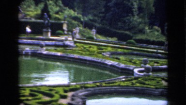 1957: a few groups of people walk in a garden overlooking a lake ENGLAND