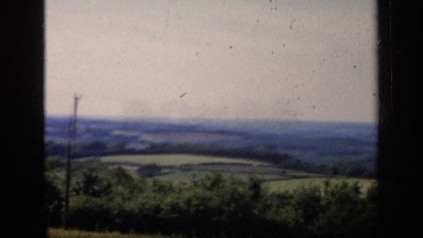 1957: countryside is patchwork of land in green, gray and blue under the sky