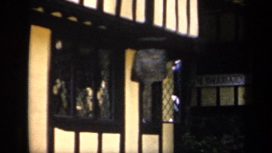 1957: a wood and stucco building houses shops alongside a walkway ENGLAND
