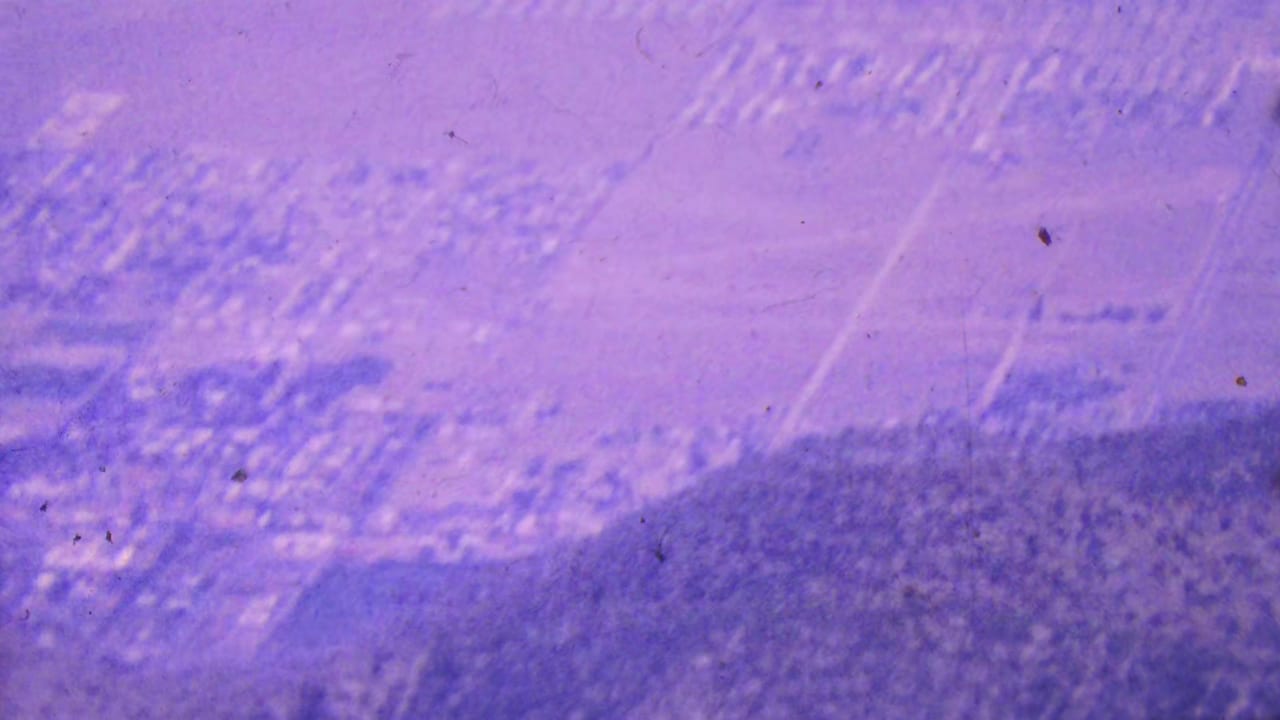 A high 1964 Palm Springs view shows clustered buildings and road patterns near darker arid hills, softened by grain, haze, and motion blur.