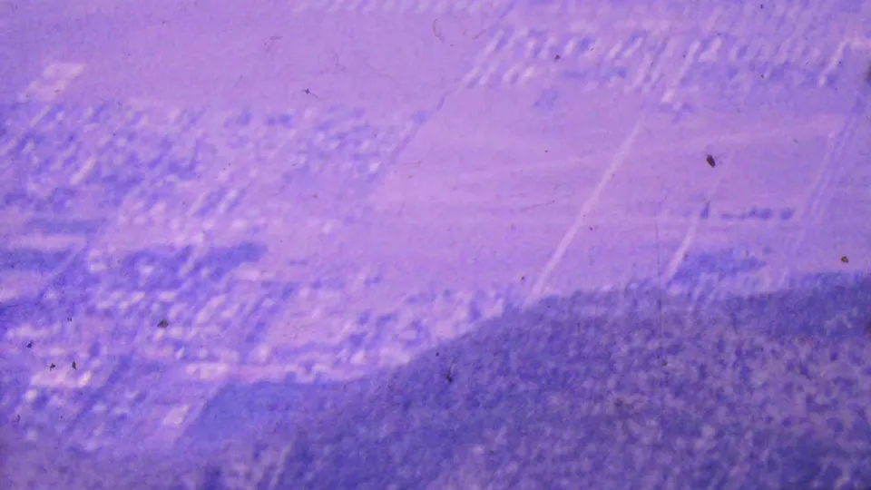 A high 1964 Palm Springs view shows clustered buildings and road patterns near darker arid hills, softened by grain, haze, and motion blur.
