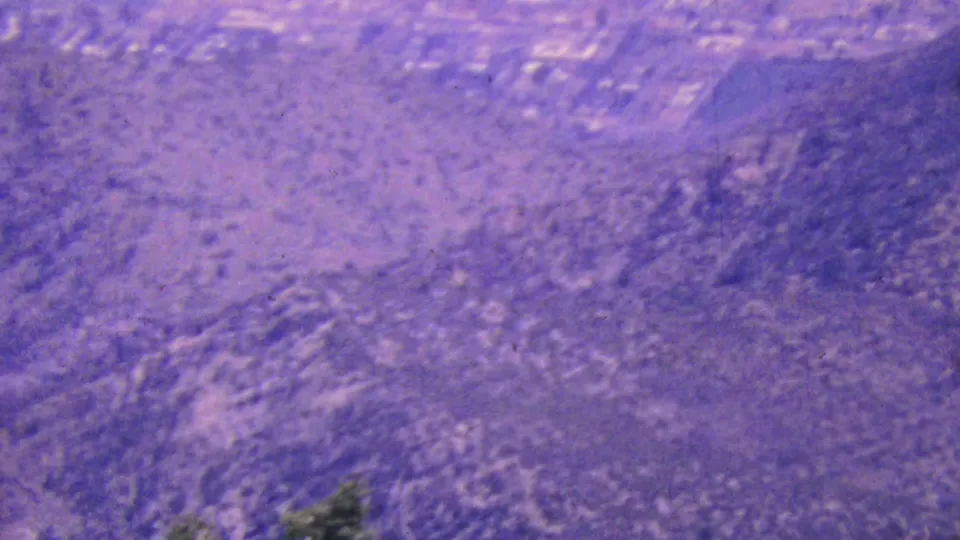 A final 1964 Palm Springs aerial frame shows blurred arid hills, sparse vegetation, and faint developed land patterns beneath a pronounced vintage color shift.