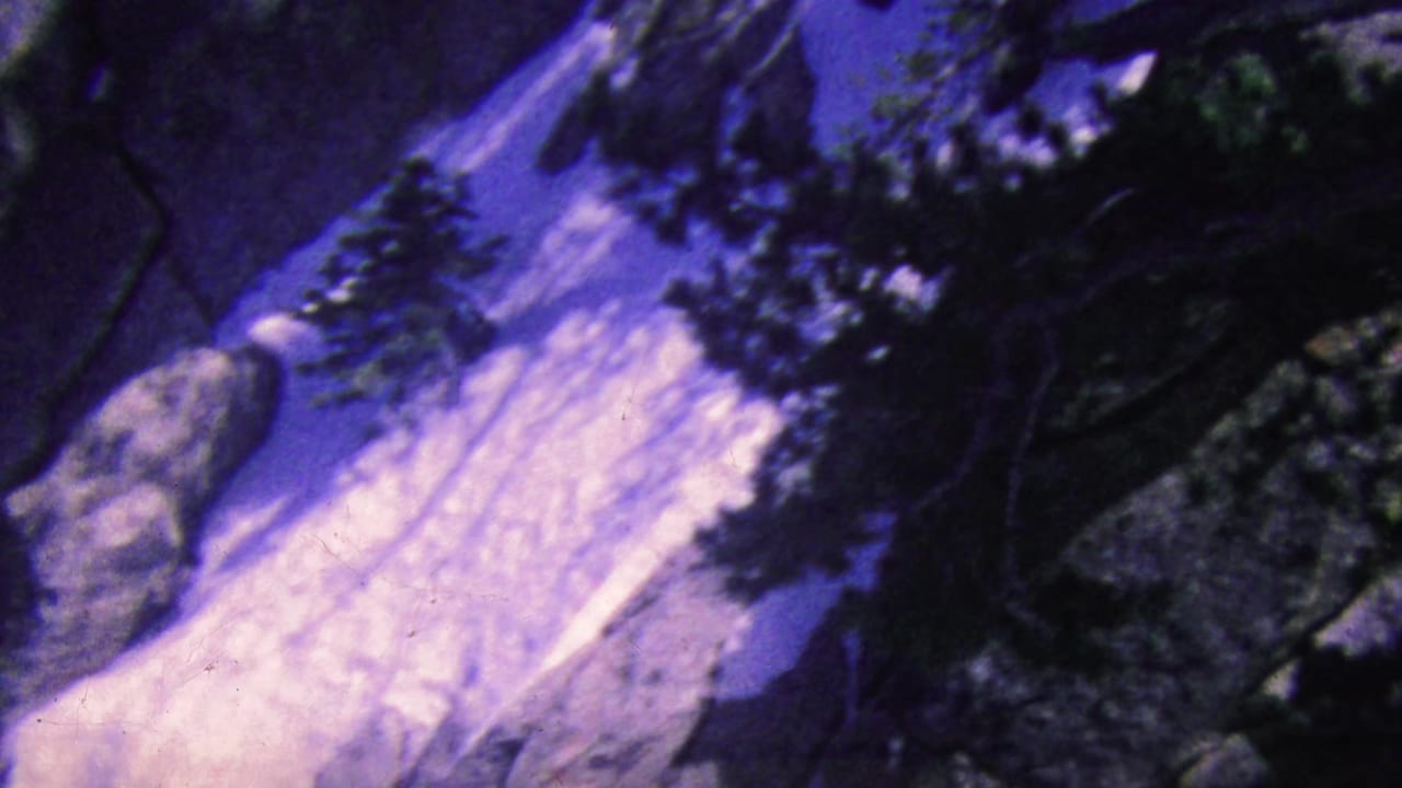 Wide view of older tourists waving from a balcony near a rocky mountainside.