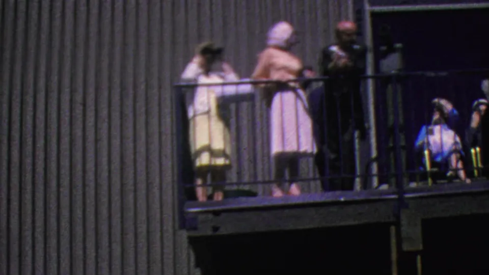 The final frame shows the Palm Springs tramway balcony with adults in period clothing and a young girl at the right holding binoculars, framed by metal railings and vertical wall siding.