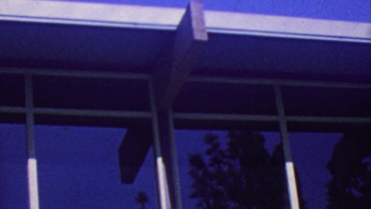 Reflective modernist windows and white beams against a deep blue sky.