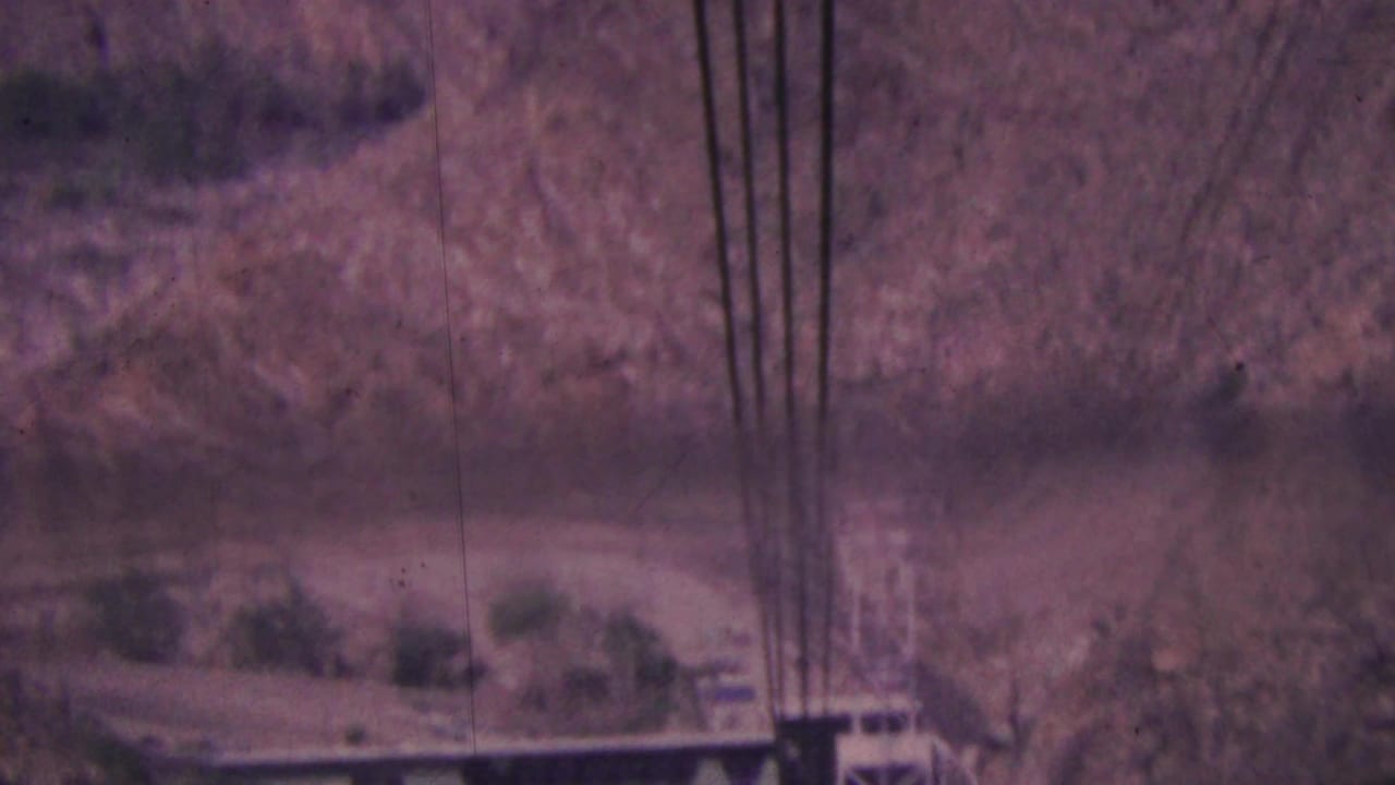 A tramway support tower and cables are visible over a steep desert canyon.