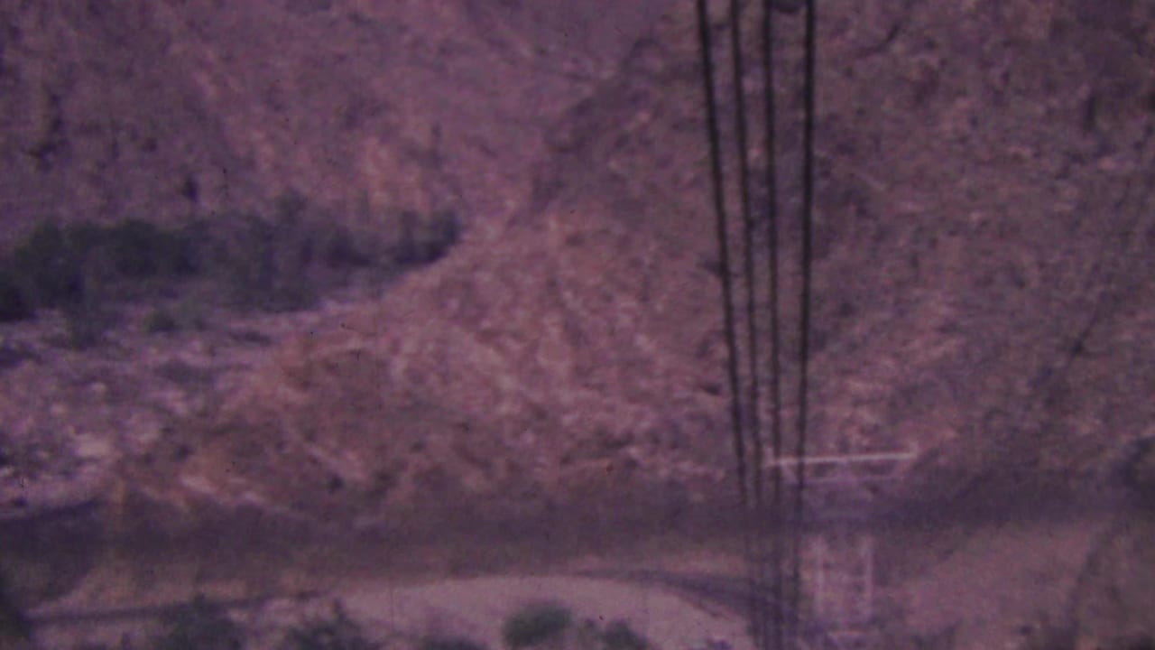 Several dark cables pass in front of a dry slope and a road at the base of the frame.