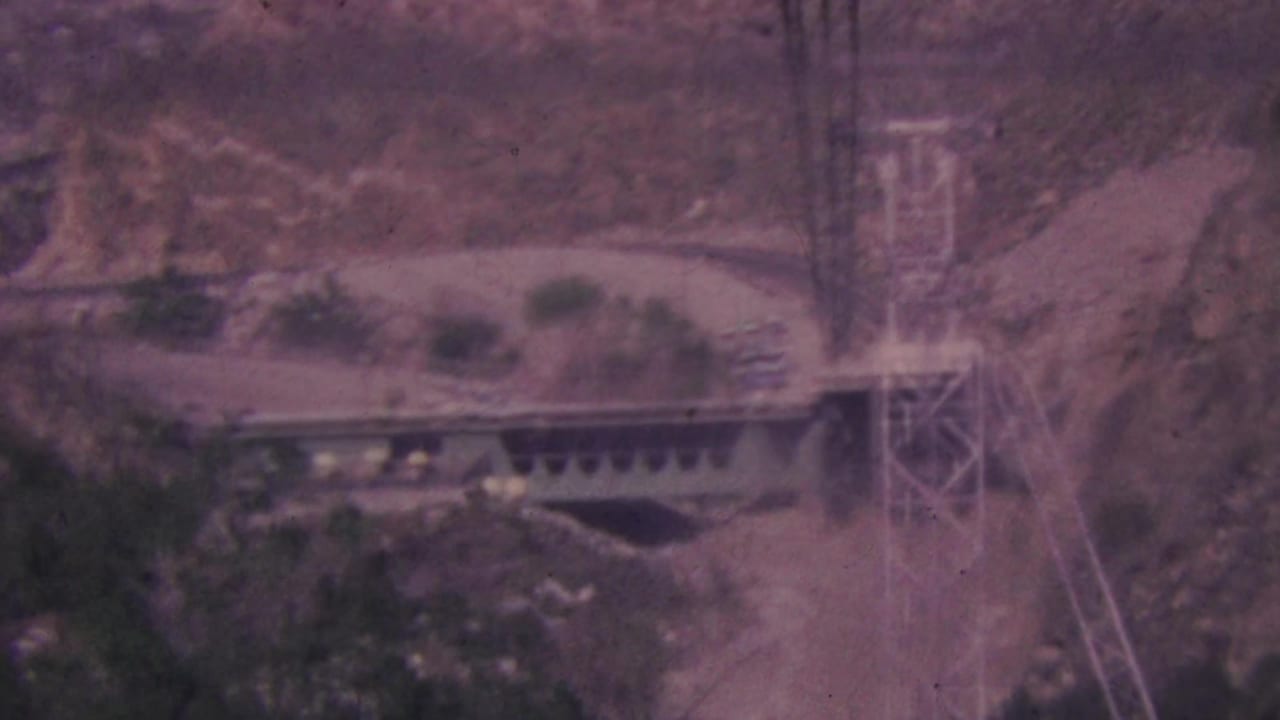 A Palm Springs tramway platform and tower appear along the desert canyon terrain, with the frame softened by faded color and handheld 8mm exposure.