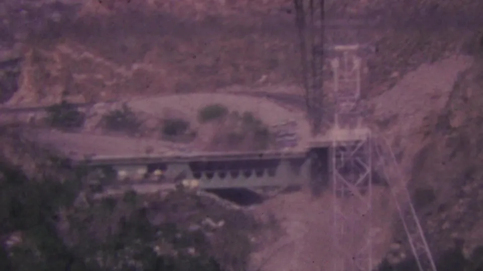 A Palm Springs tramway platform and tower appear along the desert canyon terrain, with the frame softened by faded color and handheld 8mm exposure.