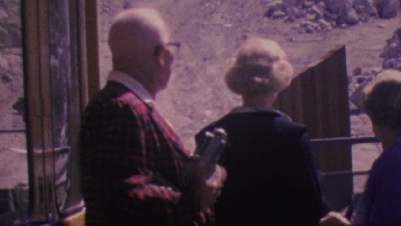 An older man in a plaid jacket stands beside two women at an open tram doorway.