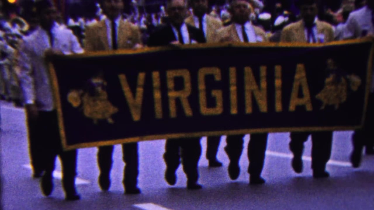 The large VIRGINIA banner passes close to the camera in the 1963 Indiana parade, with multiple adult marchers and spectators visible behind it.
