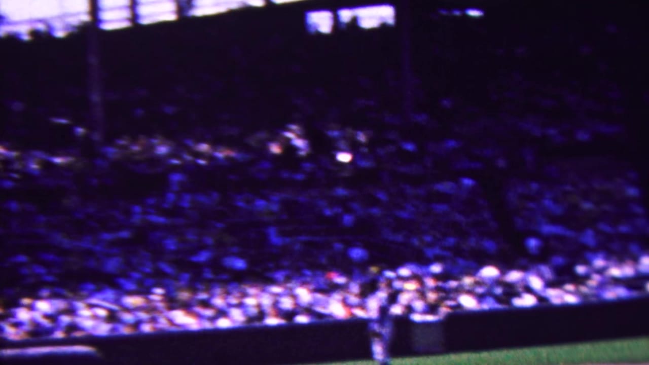1963 Indiana home-movie view of packed stadium seating above the baseball field, with a uniformed player partly visible near the lower edge.
