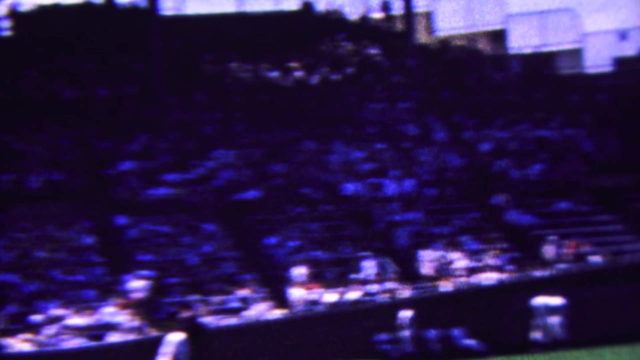 Blurred stadium crowd and field edge during a baseball game.
