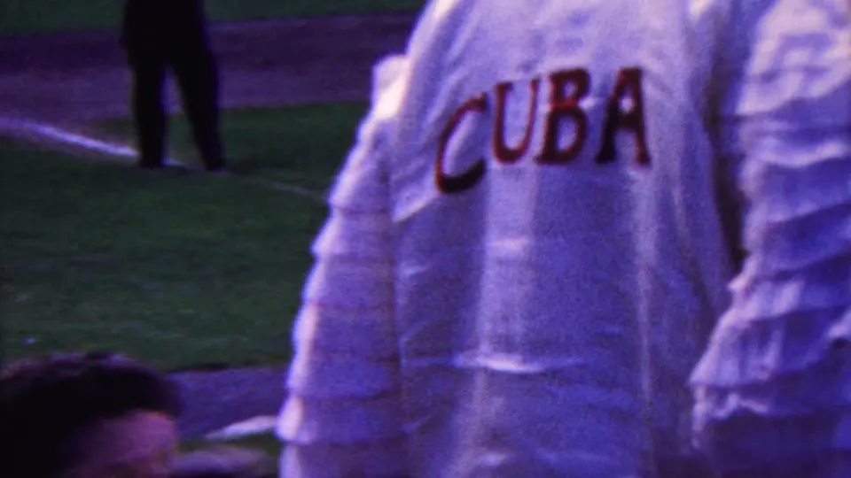 Close spectator-side view of a ruffled white baseball jersey with red lettering near the field during a 1963 Indiana ballpark home movie.