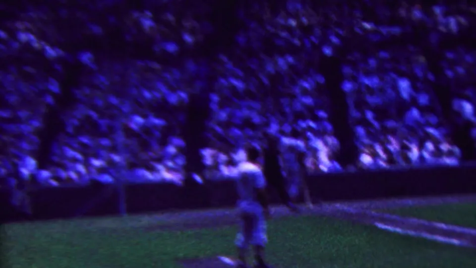 Wide 1963 8mm view from the stands in Indiana, with a player on the field and a dense stadium crowd in the background.